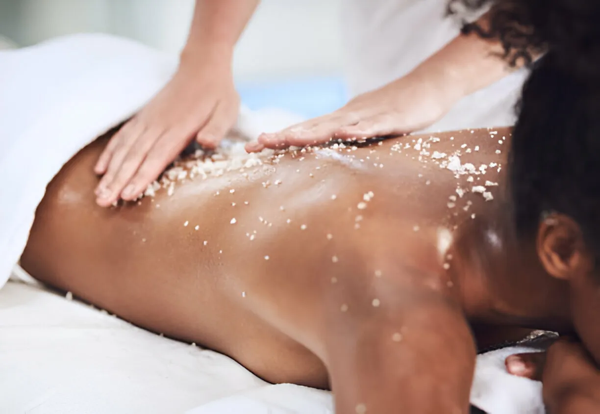 Mineral salt body scrub being massaged across the back during a full-body exfoliation treatment at Legacy Aesthetic, Edmonton