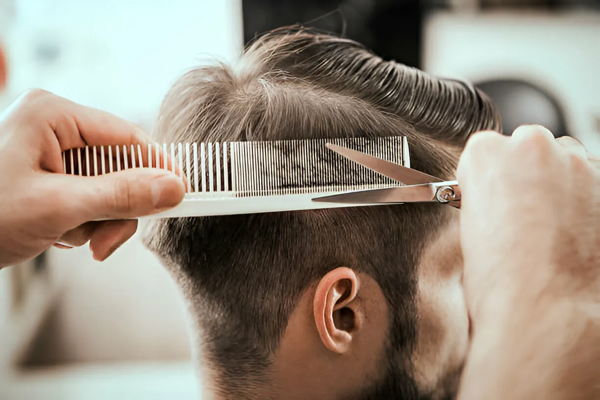 Precise men’s haircut with comb and scissors creating a sharp, clean style at Legacy Aesthetic, Edmonton